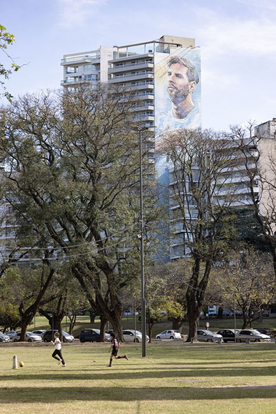 Picture of Kids playing football under the bigger-than-life painting of Rosarian MessiRosario - Argentina