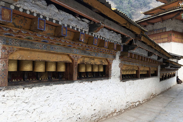 Picture of Part of the circumambulation with prayer wheels and the temple in the backgroundGom Kora - Bhutan