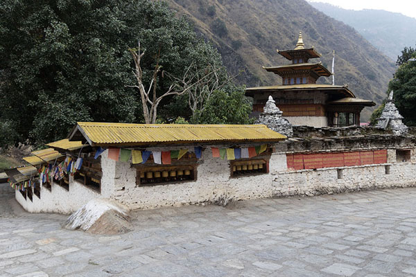 Picture of Prayer wheels and the temple of Gom Kora in the backgroundGom Kora - Bhutan
