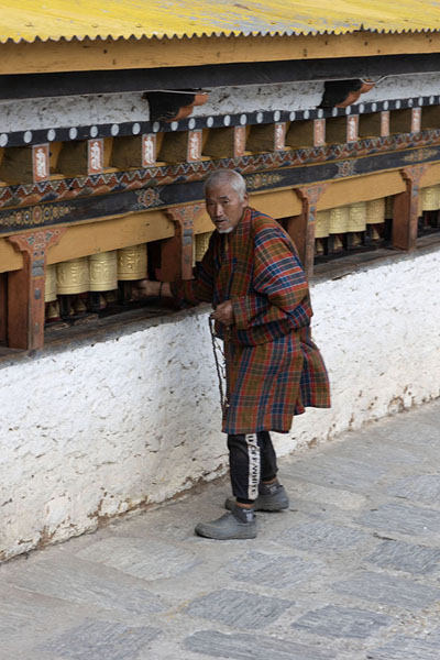 Foto de Old man turning the prayer wheels at Gom KoraGom Kora - ButÃ¡n