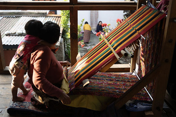 Foto van Woman with child weaving a colourful fabricKhoma - Bhutan