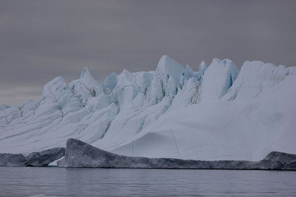 Ragged iceberg under a cloudy sky at the mouth of the icefjord at Ilulissat | Ilulissat Icefjord | Greenland