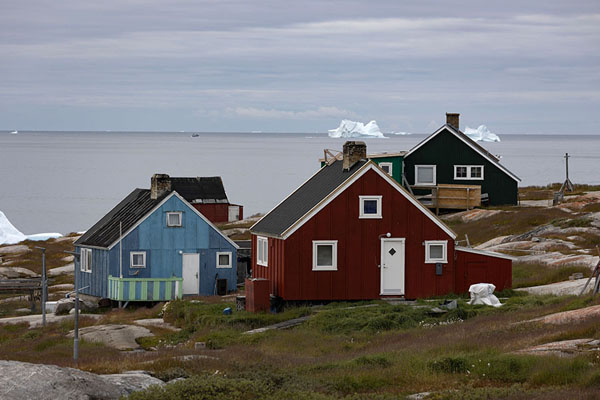 Picture of Oqaatsut (Greenland): Icebergs floating in the ocean behind the colourful houses of Oqaatsut