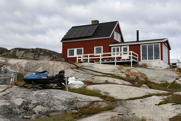 Picture of Snowmobile parked below a typical red house in Oqaatsut