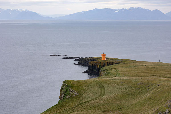 Looking out over the south side of Grímsey island with lighthouse and the mountains of Iceland in the background | Isola di Grímsey | Islanda