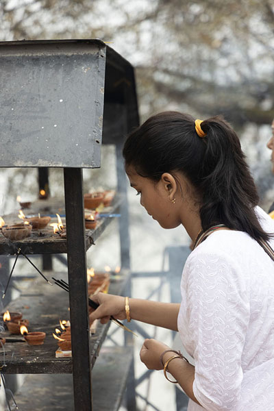 Foto de Young girl lighting a candle at Umananda temple on Peacock IslandGuwahati - India