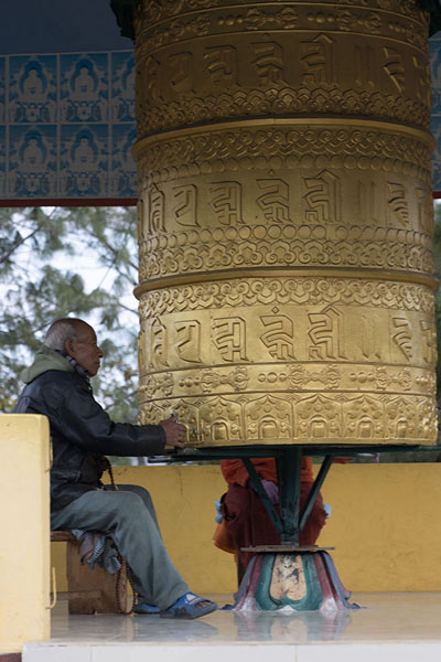 Foto van Man turning a huge prayer wheel at the entrance of Zangpokdalri monasteryZangpokdalri - India